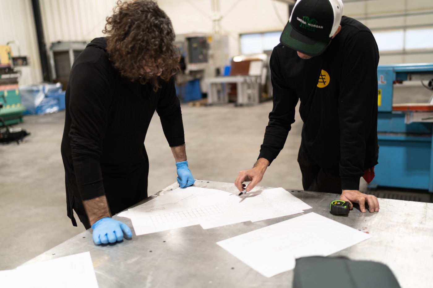 Fabrication team reviewing engineering blueprints on a steel workbench