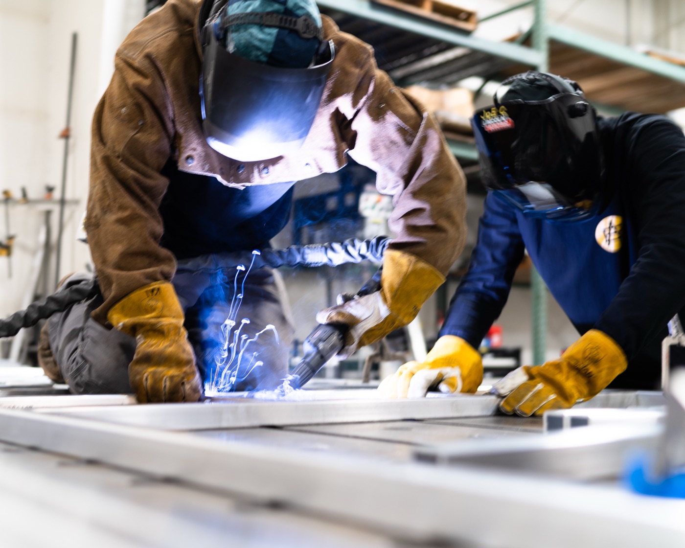 Joe Clark and team welding the aluminum frame — Joe Clark's name visible on helmet