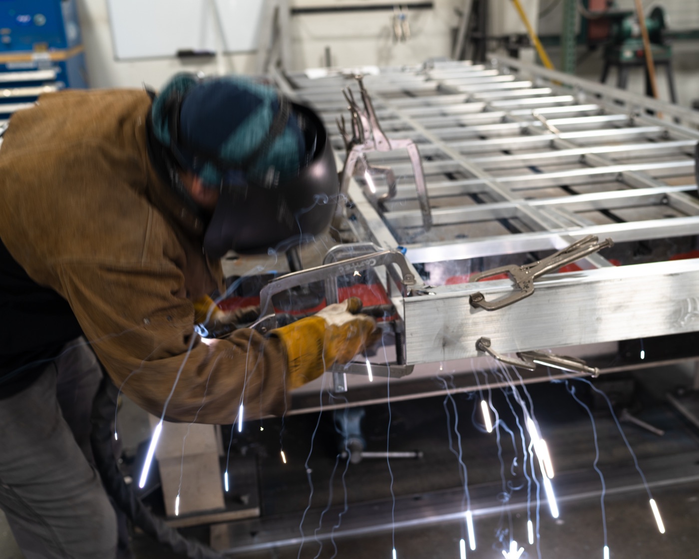 Welder with sparks flying as the roof rack frame is welded