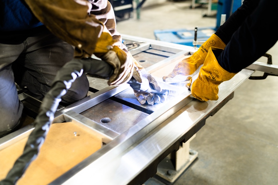 Two skilled fabricators working the aluminum frame together